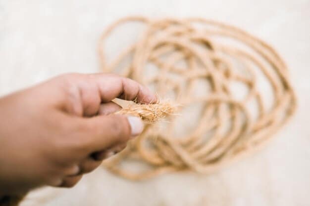 A close-up shot of a person's hands carefully wrapping sisal rope around a sturdy wooden post, creating a durable scratching surface for a DIY cat tree. The image highlights the tactile nature of the project and the quality of the materials used.