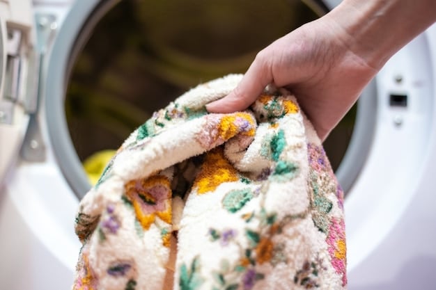 A washing machine with a removable dog bed cover being loaded inside. The cover is made of colorful, patchwork-style fabric, and a bottle of gentle laundry detergent sits on top of the machine.