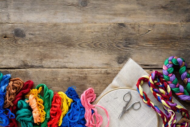 A top-down view of a crafting table cluttered with colorful fabric scraps, sewing supplies (needles, thread, scissors), and a small pile of dried catnip. Several partly sewn cat toys in various shapes (mice, fish, balls) are scattered around, giving a sense of the creative process and the materials involved in making homemade catnip toys.