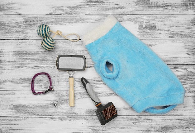 A close-up shot of the materials needed for making a DIY dog cooling mat. The items include blue cotton fabric, several blue gel ice packs, a pair of scissors, a sewing needle, and a spool of thread, all arranged neatly on a wooden tabletop.