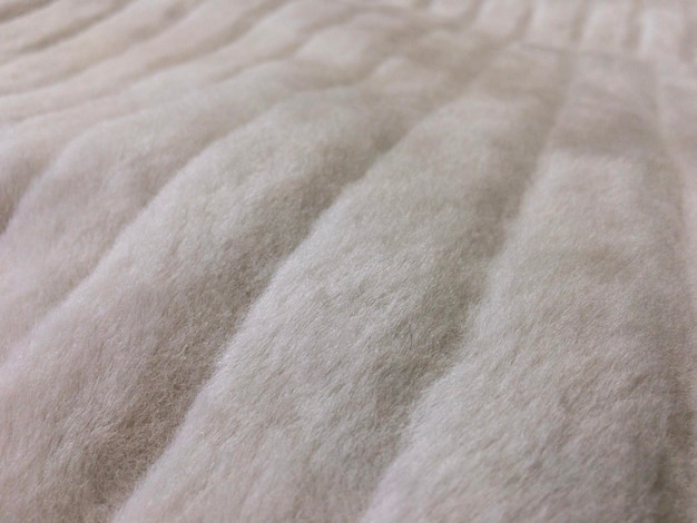 A close-up shot of the fabric of a calming bed. The material is a very soft, plush faux fur in a light beige color. The texture looks inviting and comfortable.
