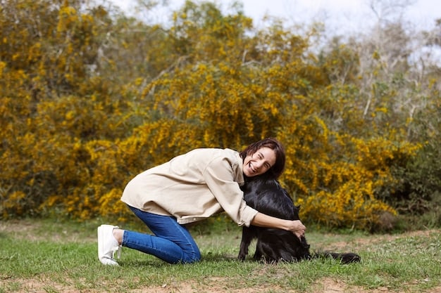 A person giving a small treat to a dog that is squatting to urinate on a patch of grass. The person is smiling and praising the dog with a cheerful tone.