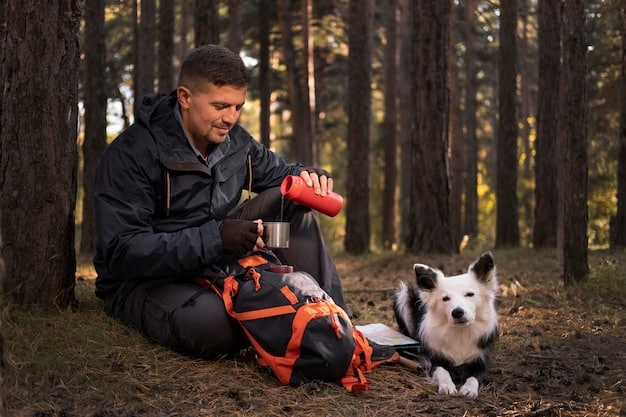 A dog wearing a backpack sits and waits patiently, while a person prepares a clicker and treat. The setting appears to be a hiking trail.