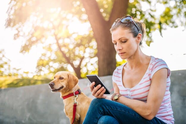 A pet owner using a smartphone app to monitor their dog's activity levels and vital signs.